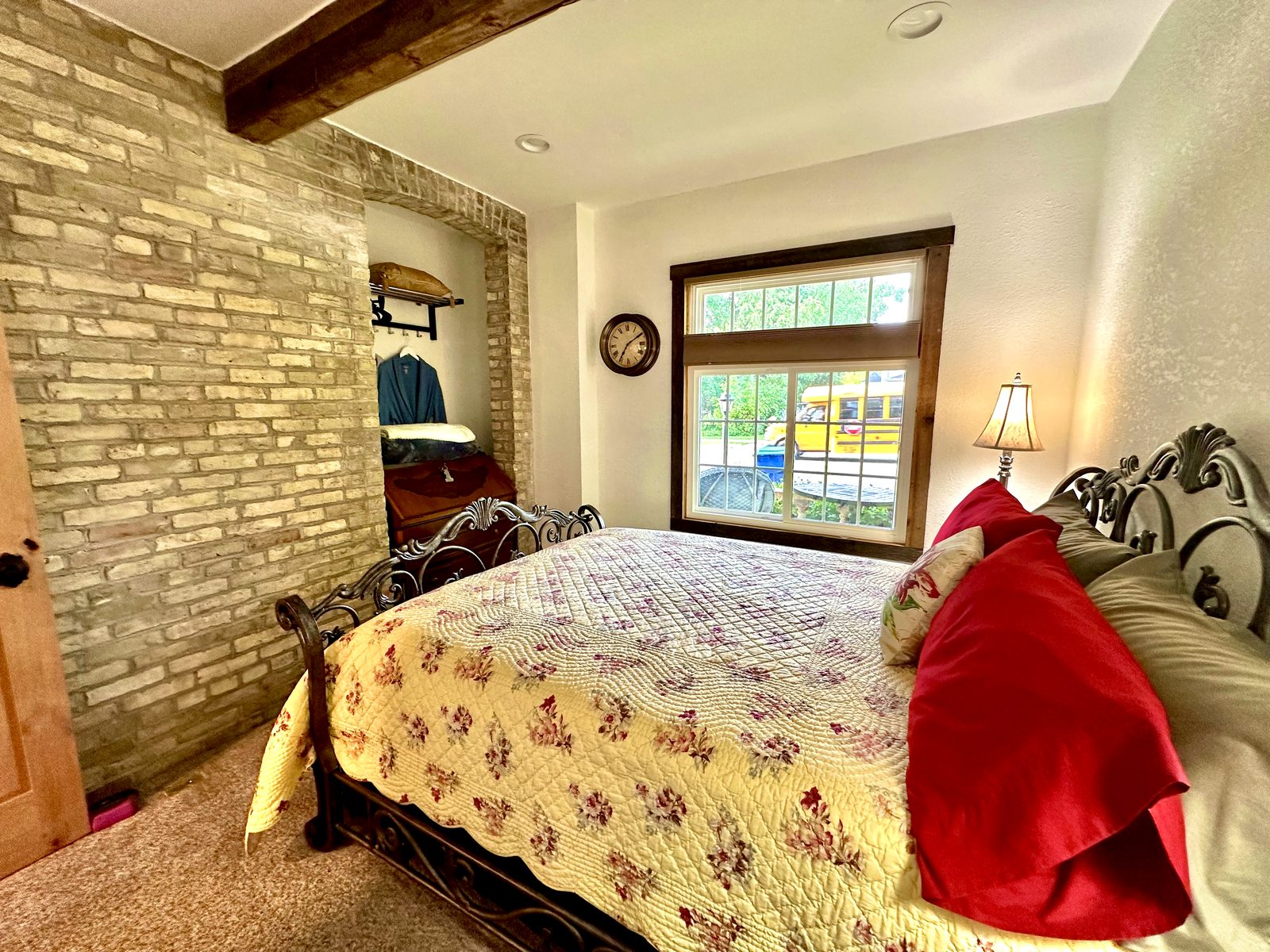 Queen wrought-iron bed beside an exposed Cream City Brick wall