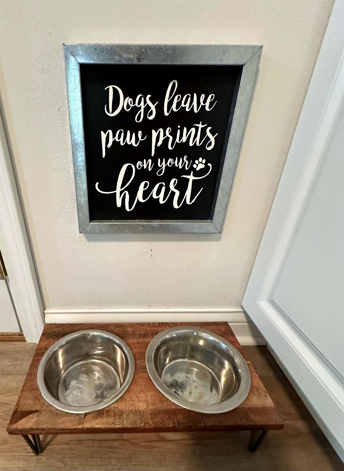 Dog bowls beneath a Dogs leave paw prints on your heart sign
