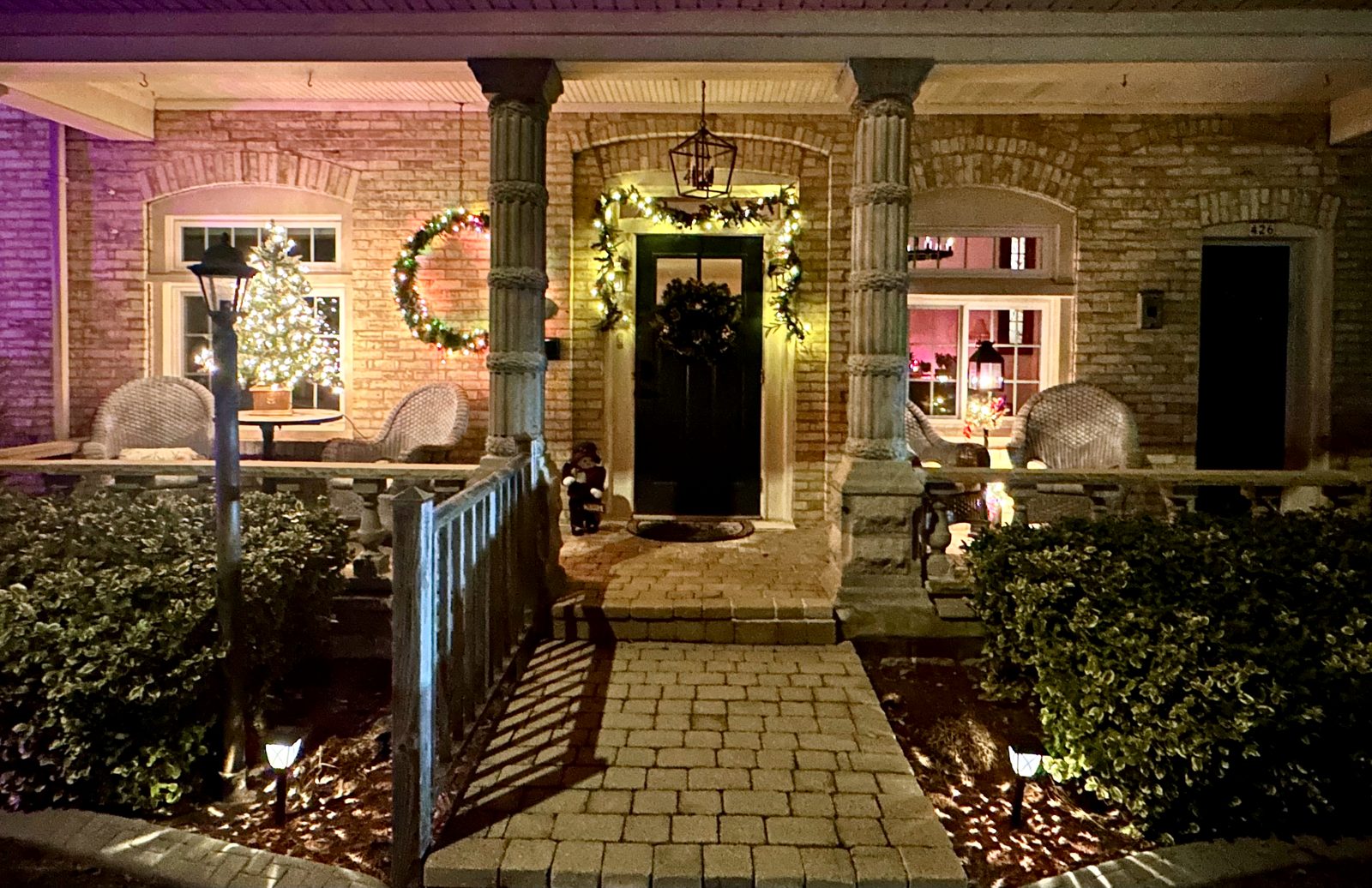 Front porch and Cream City Brick house decorated for the holidays at night