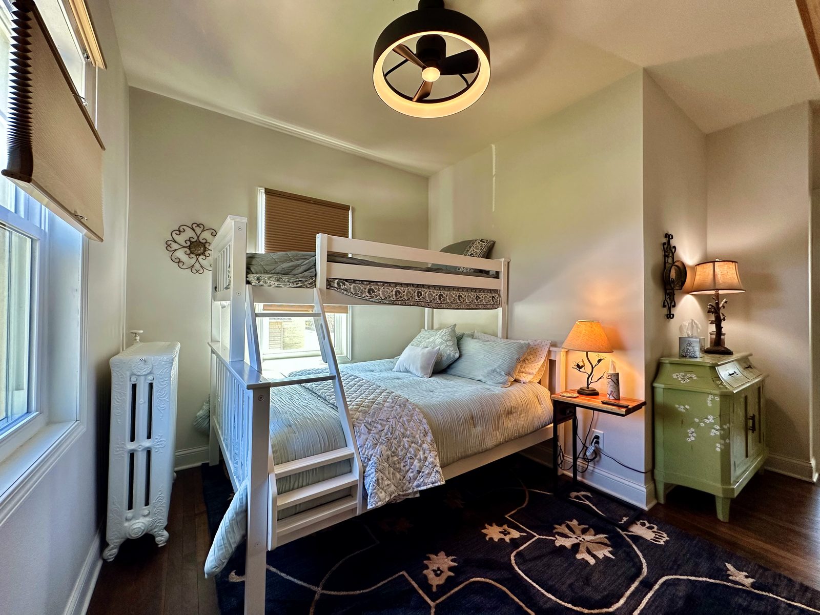 Bunk room with white bunk beds, lower double bed, and ceiling fan