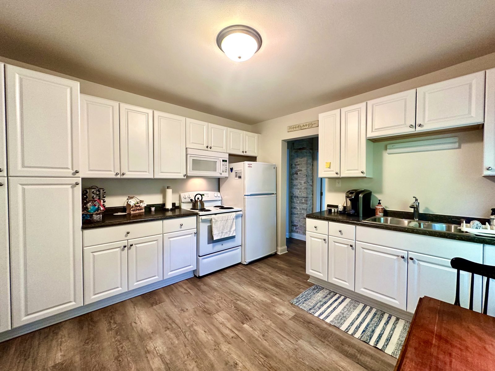 Kitchen with white cabinets, refrigerator, stove, and sink