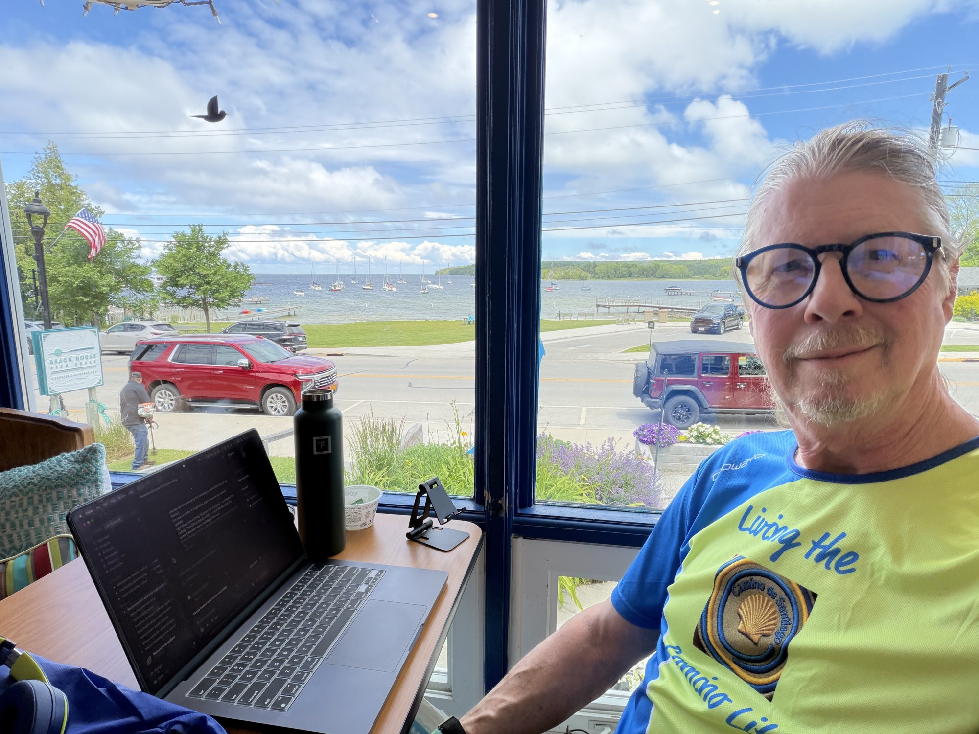 Dave writing at Blue Horse Cafe in Door County, Wisconsin with Lake Michigan behind him